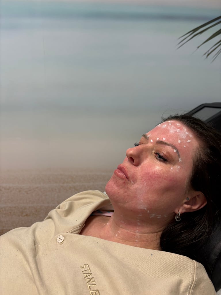 Woman with sunscreen on her face relaxing on a beach chair with ocean and palm trees in background